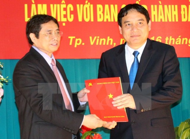 Đồng chí Phạm Minh Chính (trái) trao quyết định của Bộ Chính trị và tặng hoa tân Bí thư Tỉnh ủy Nghệ An Nguyễn Đắc Vinh. Nguồn ảnh TTXVN